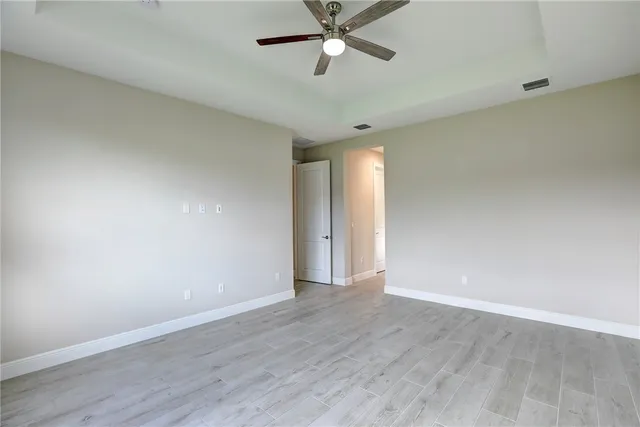 a view of an empty room with window a ceiling fan and wooden floor
