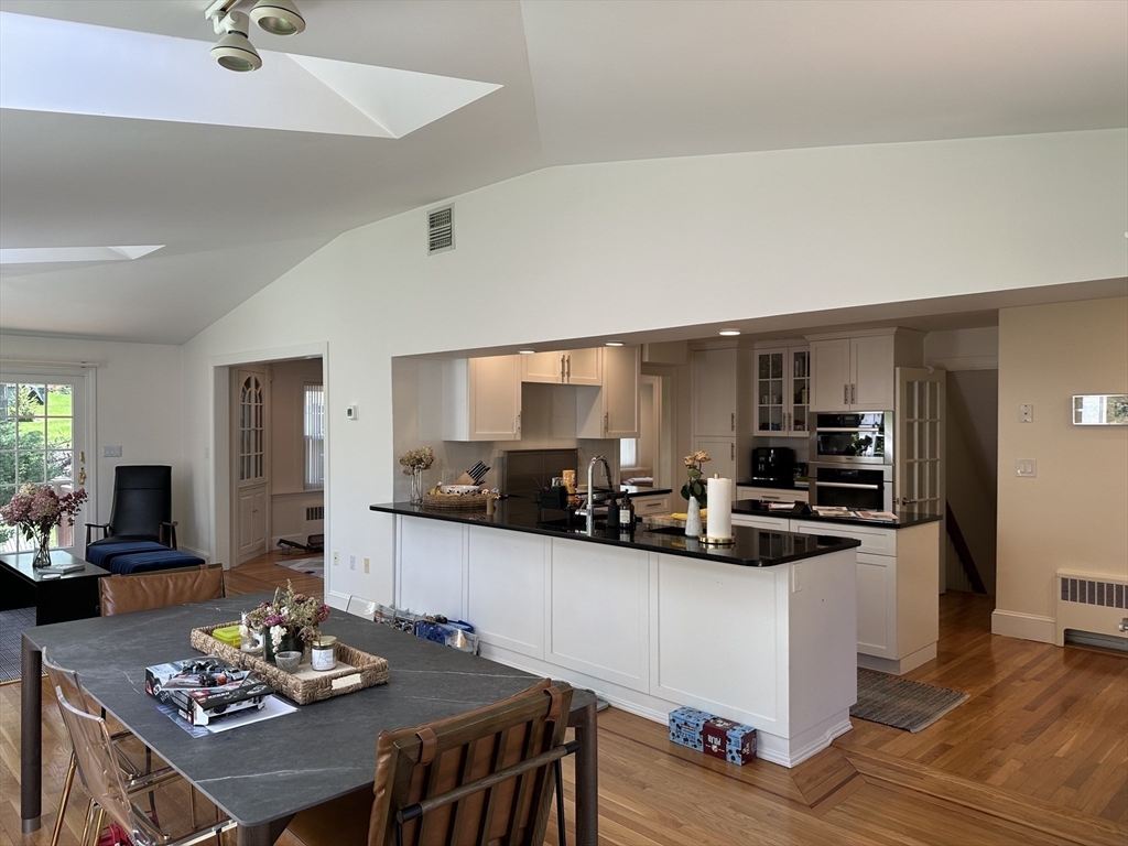 45 Wellesley Road Belmont, MA 02478 - Photo 10 of 39 a kitchen with stainless steel appliances kitchen island granite countertop a sink dishwasher a stove a refrigerator a dining table and chairs with wooden floor