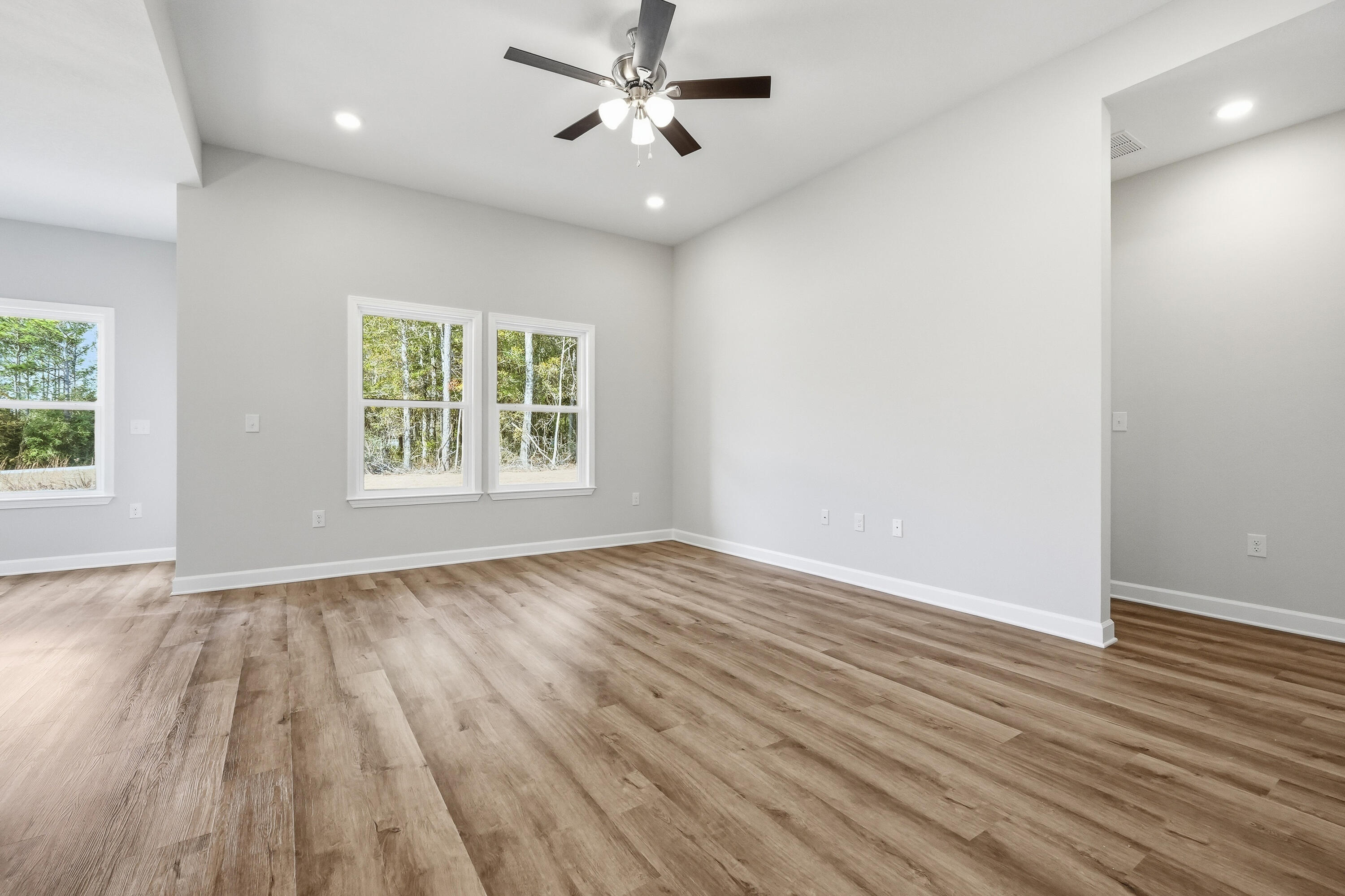 6102 Mildreds Way Crestview, FL 32539 - Photo 5 of 25 an empty room with wooden floor chandelier fan and windows