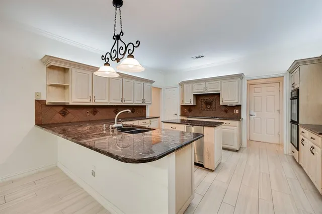 a kitchen with stainless steel appliances granite countertop a stove top oven a sink and white cabinets