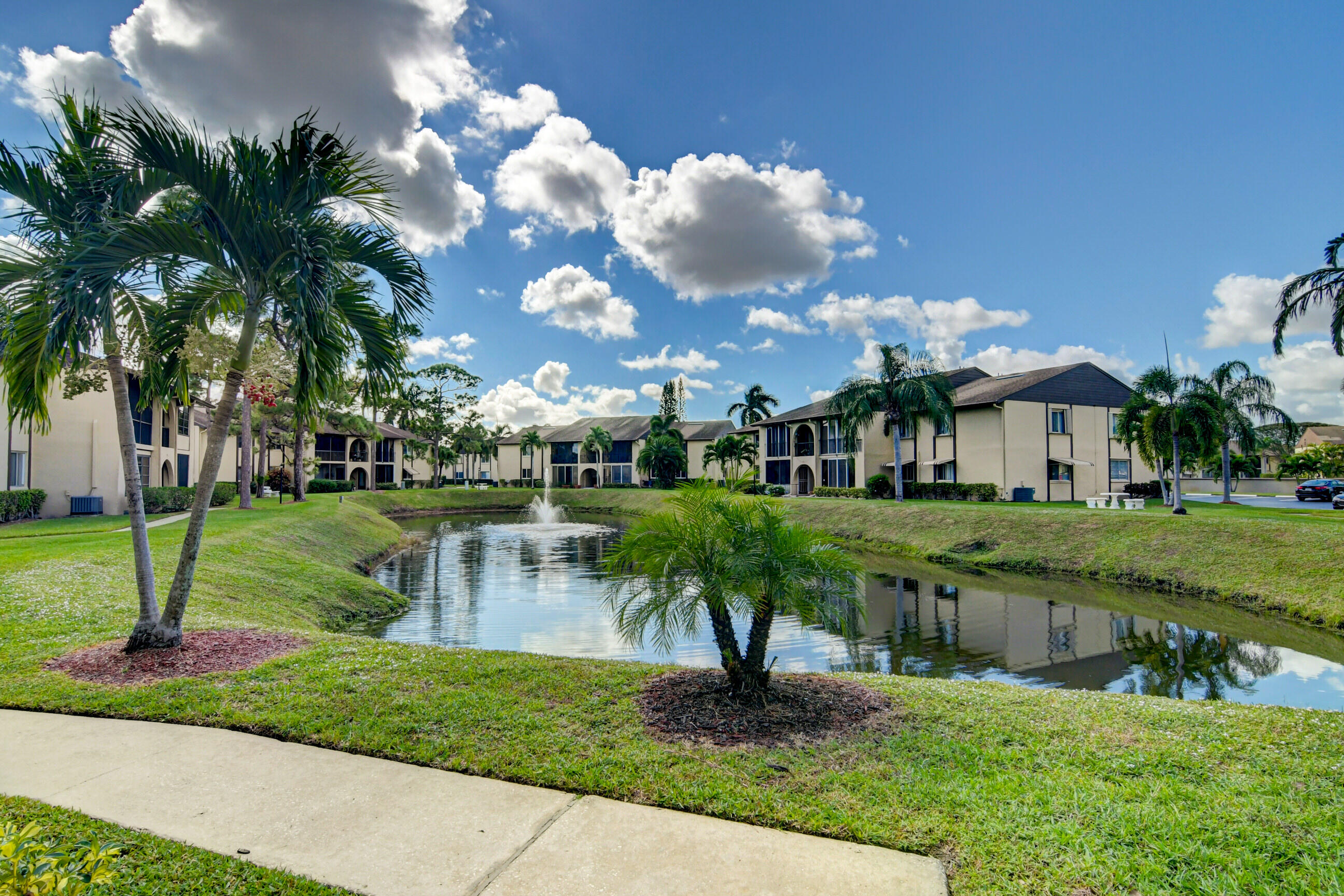 334 Pine Ridge Circle, Unit B1 Greenacres, FL 33463 - Photo 19 of 26 a front view of a house with garden and a sitting area