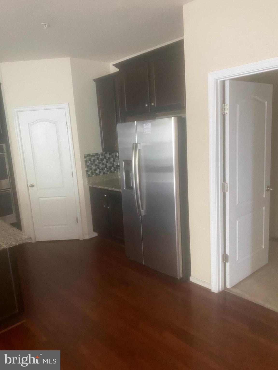 9509 Manor Oaks View Upper Marlboro, MD 20772 - Photo 4 of 20 a view of a refrigerator in kitchen and an empty room with wooden floor
