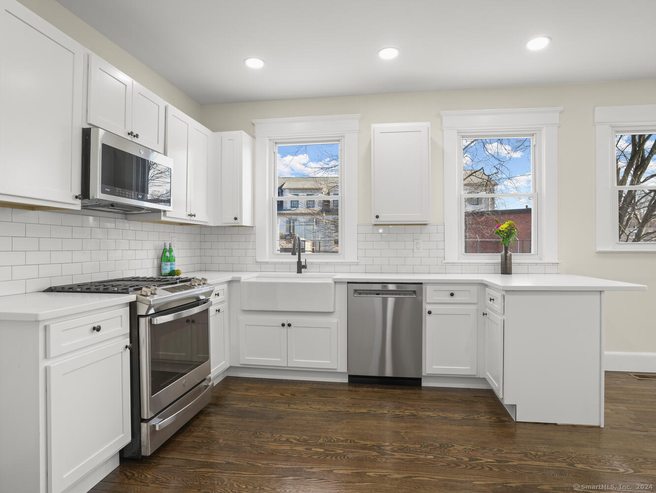 a kitchen with granite countertop white cabinets a sink a window and stainless steel appliances