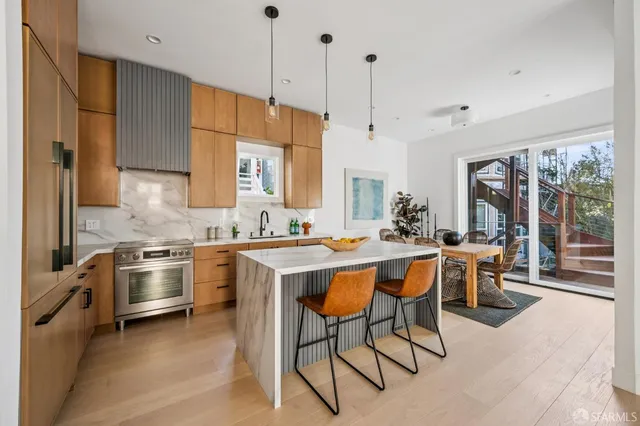 a kitchen with stainless steel appliances a stove a sink a oven a table and chairs