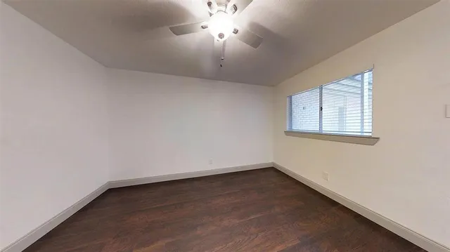an empty room with a window and a chandelier fan