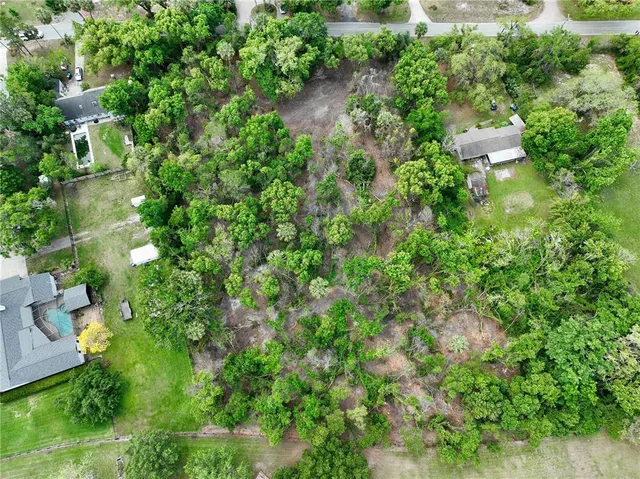 an aerial view of residential house with outdoor space and trees all around