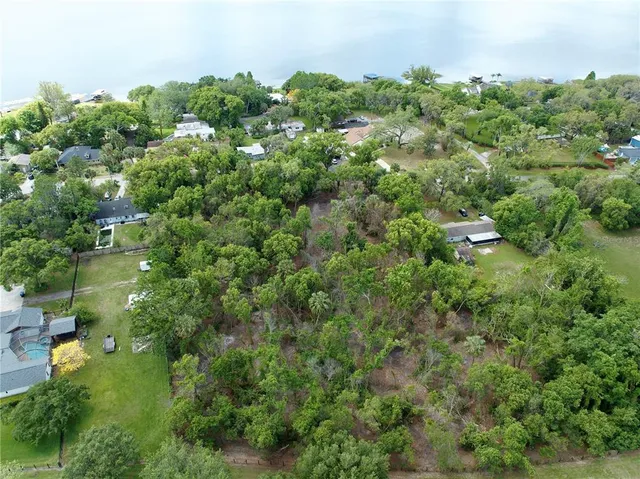 an aerial view of residential house with outdoor space and trees all around