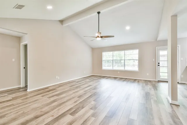 a view of an empty room with wooden floor and a window