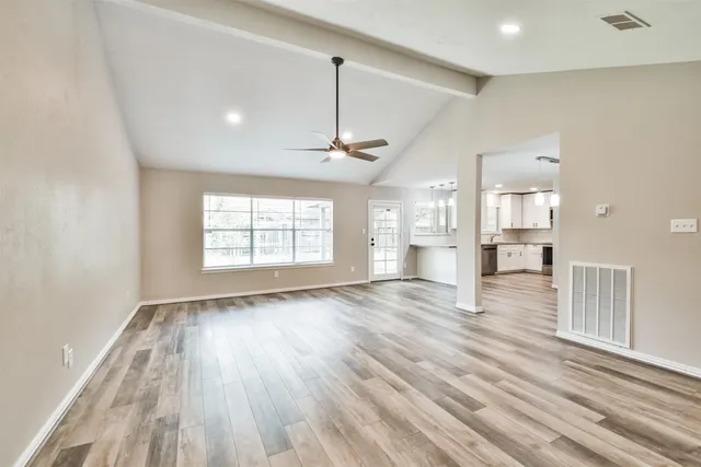 a view of empty room with wooden floor and ceiling fan