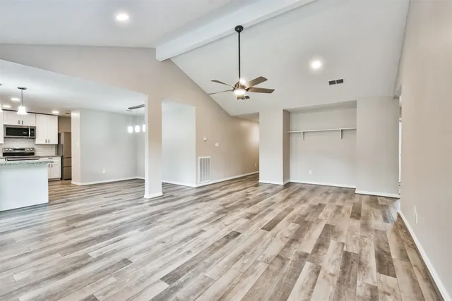 a large kitchen with granite countertop a white cabinets stainless steel appliances and a chandelier