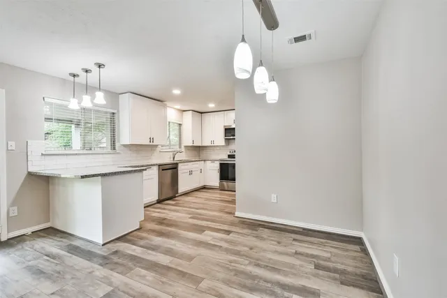 a kitchen with a stove center island a refrigerator cabinets and a wooden floor