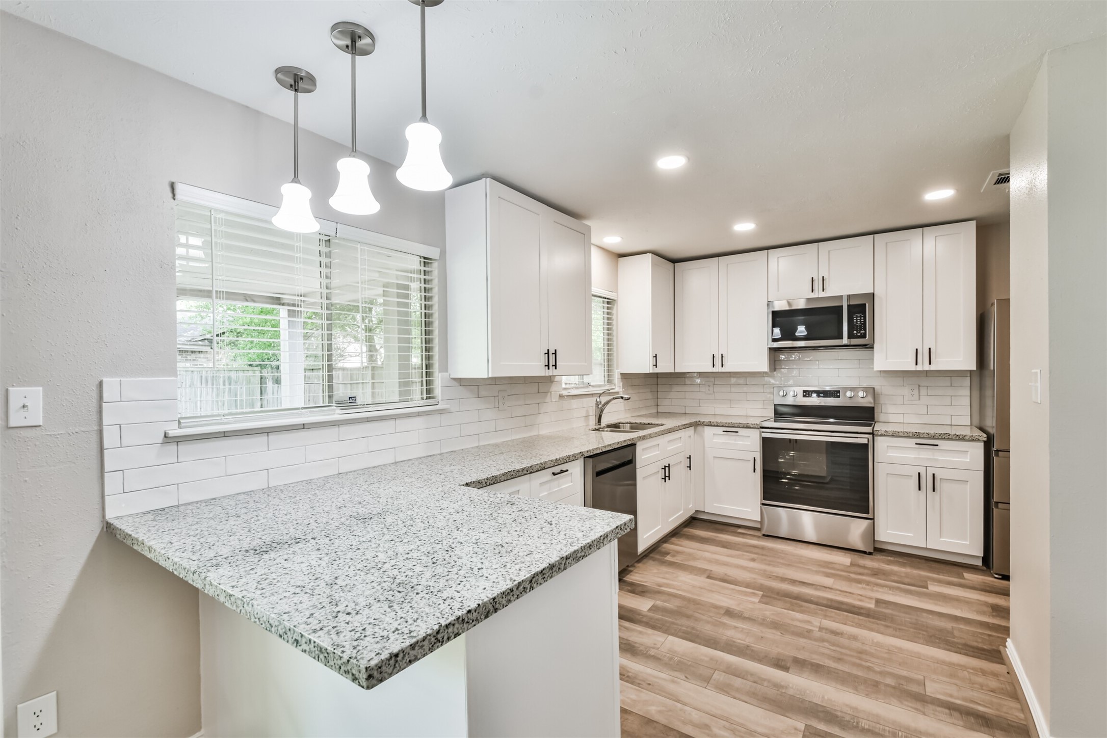 6103 Fallengate Drive Spring, TX 77373 - Photo 15 of 36 a kitchen with a stove center island a refrigerator cabinets and a wooden floor