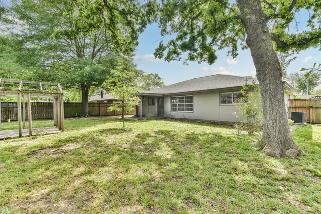 a view of a house with backyard and a large tree