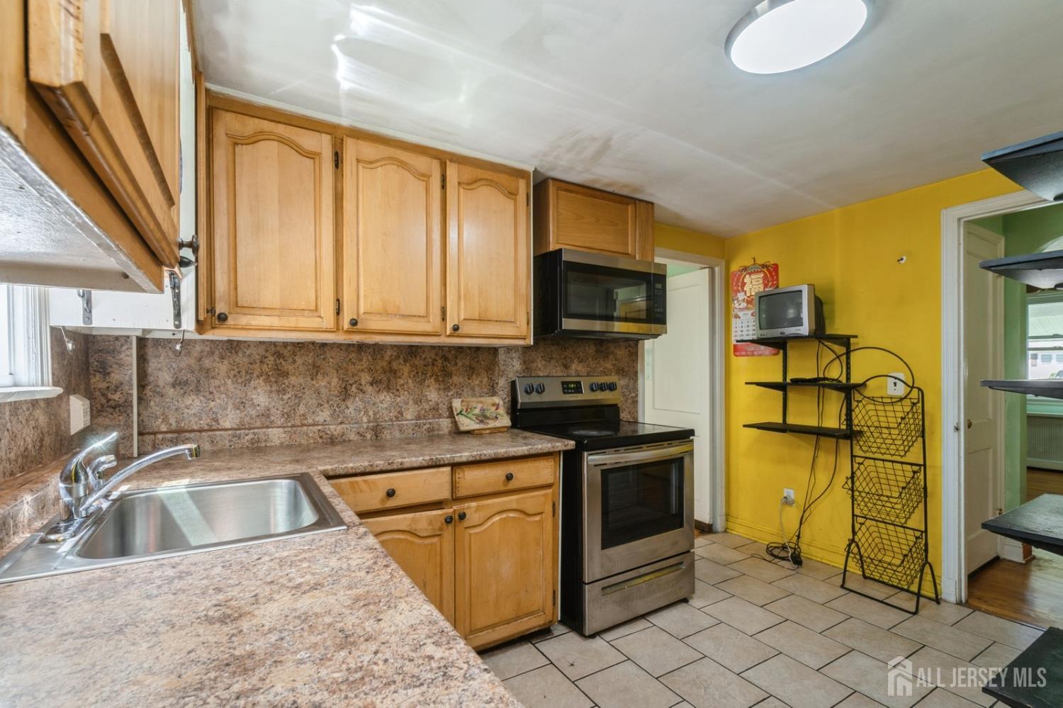 571 Greenbrook Road North Plainfield, NJ 07063 - Photo 19 of 28 a kitchen with stainless steel appliances granite countertop a sink a stove top oven a chimney next to a window