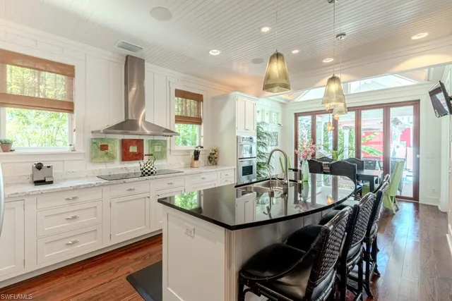 a kitchen with granite countertop a stove a sink a dining table and chairs
