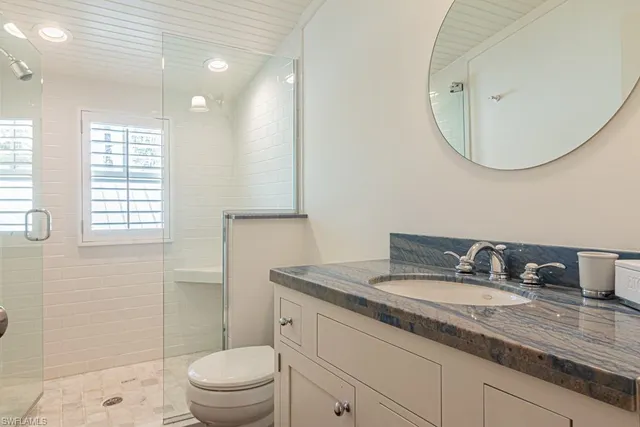 a bathroom with a granite countertop sink a toilet and a mirror