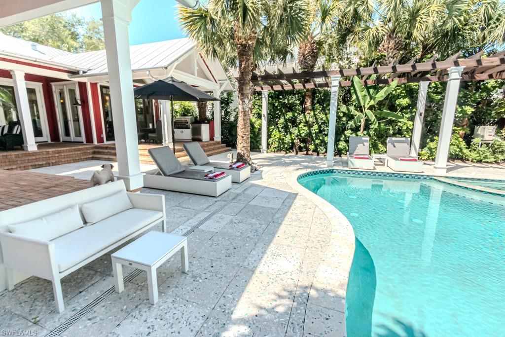 245 Broad Avenue South Naples, FL 34102 - Photo 10 of 50 a view of a swimming pool with lounge chairs in patio