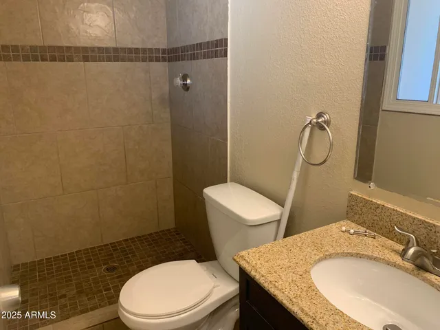 a bathroom with a granite countertop toilet sink and mirror