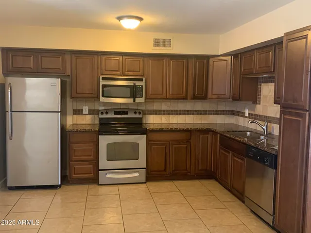 a kitchen with granite countertop a refrigerator and a stove