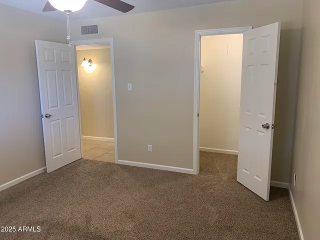an empty room with closet and a chandelier fan
