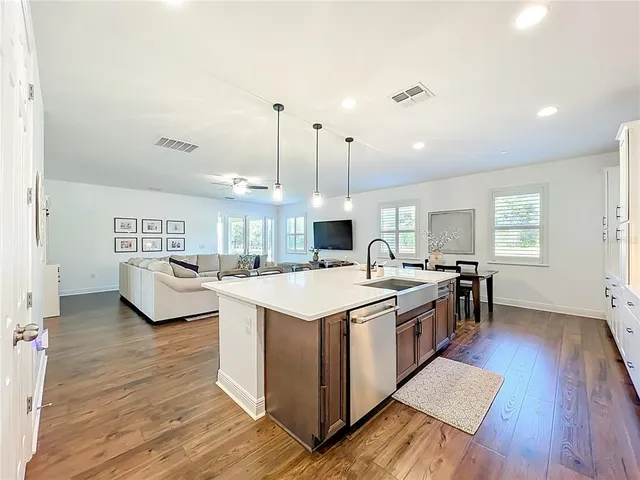 a large kitchen with stainless steel appliances a lot of counter space and a wooden floor