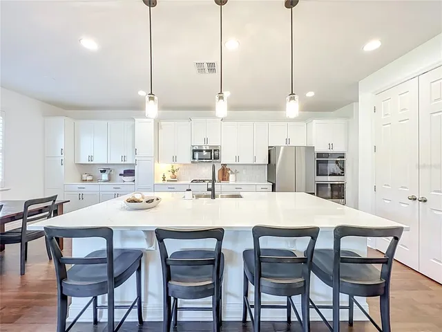 a kitchen with stainless steel appliances kitchen island granite countertop a table chairs and a refrigerator