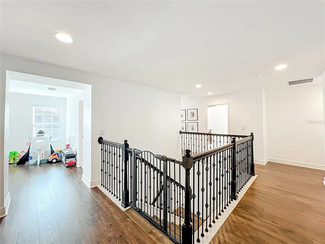 a view of a hallway with wooden floor and stairs