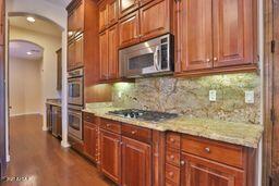 9265 East Canyon View Road Scottsdale, AZ 85255 - Photo 9 of 39 a kitchen with stainless steel appliances granite countertop a stove a sink and a microwave