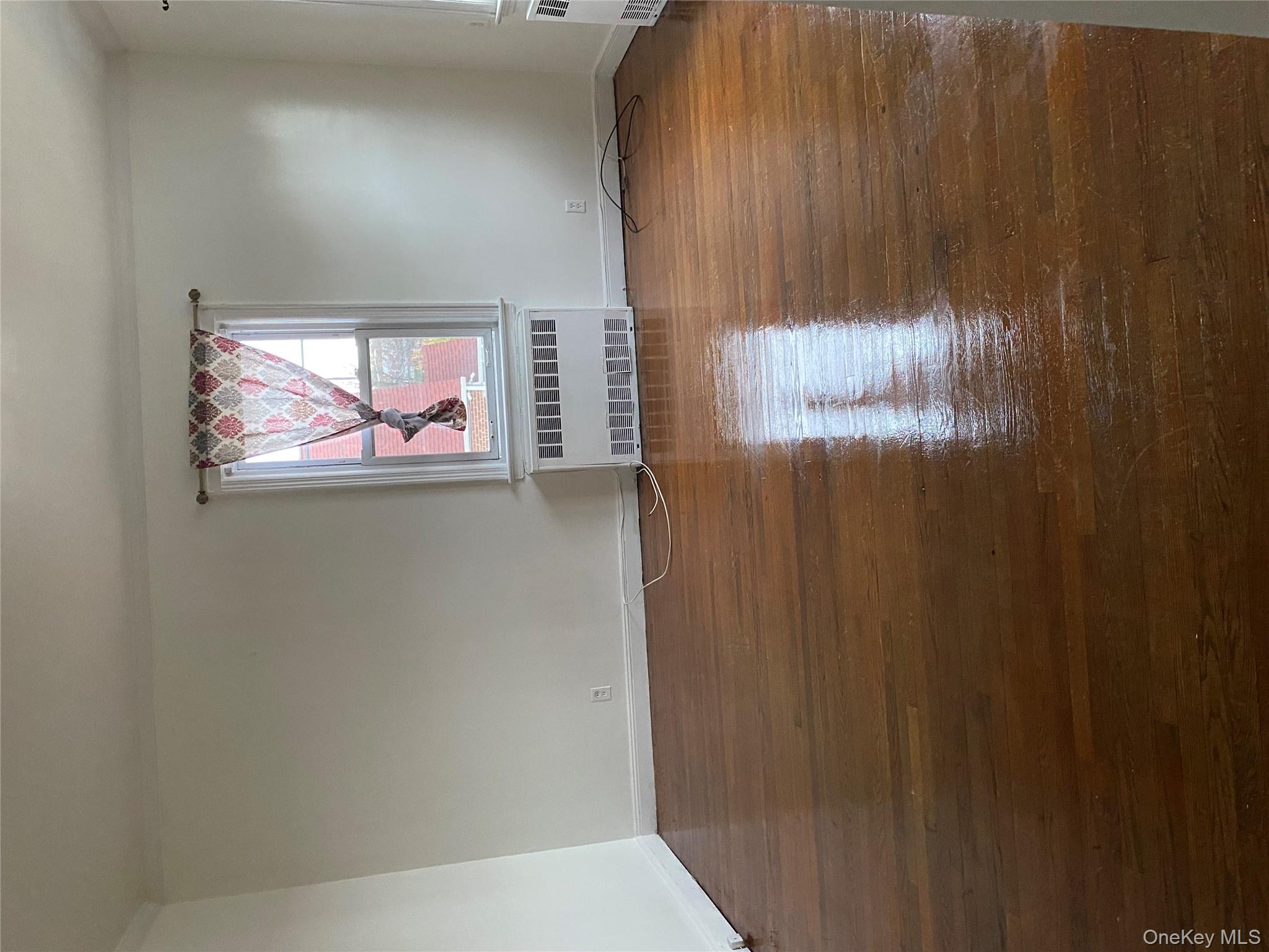 192 Beech Street Valley Stream, NY 11580 - Photo 1 of 5 a view of an empty room with wooden floor and a window