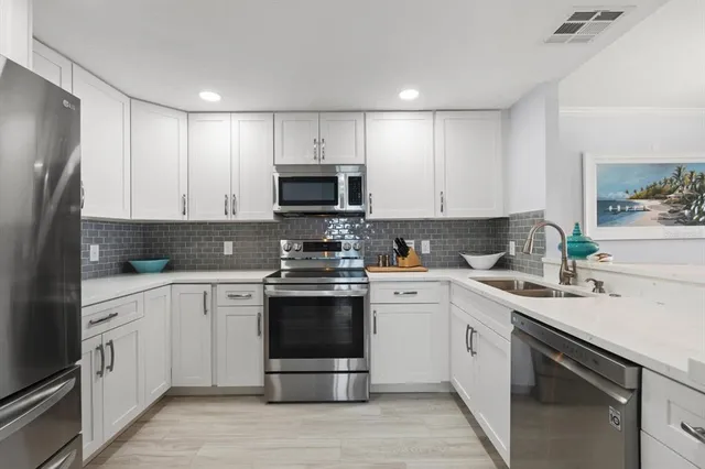 a kitchen with white cabinets and stainless steel appliances