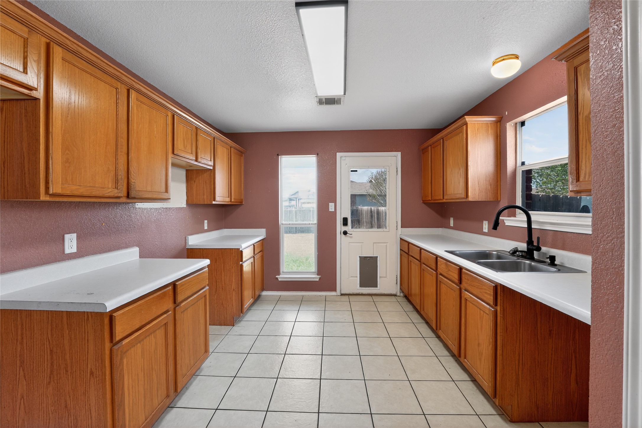 152 Eagle Drive Luling, TX 78648 - Photo 12 of 31 Kitchen featuring wood finish cabinetry, light countertops, plenty of natural light, and a textured ceiling