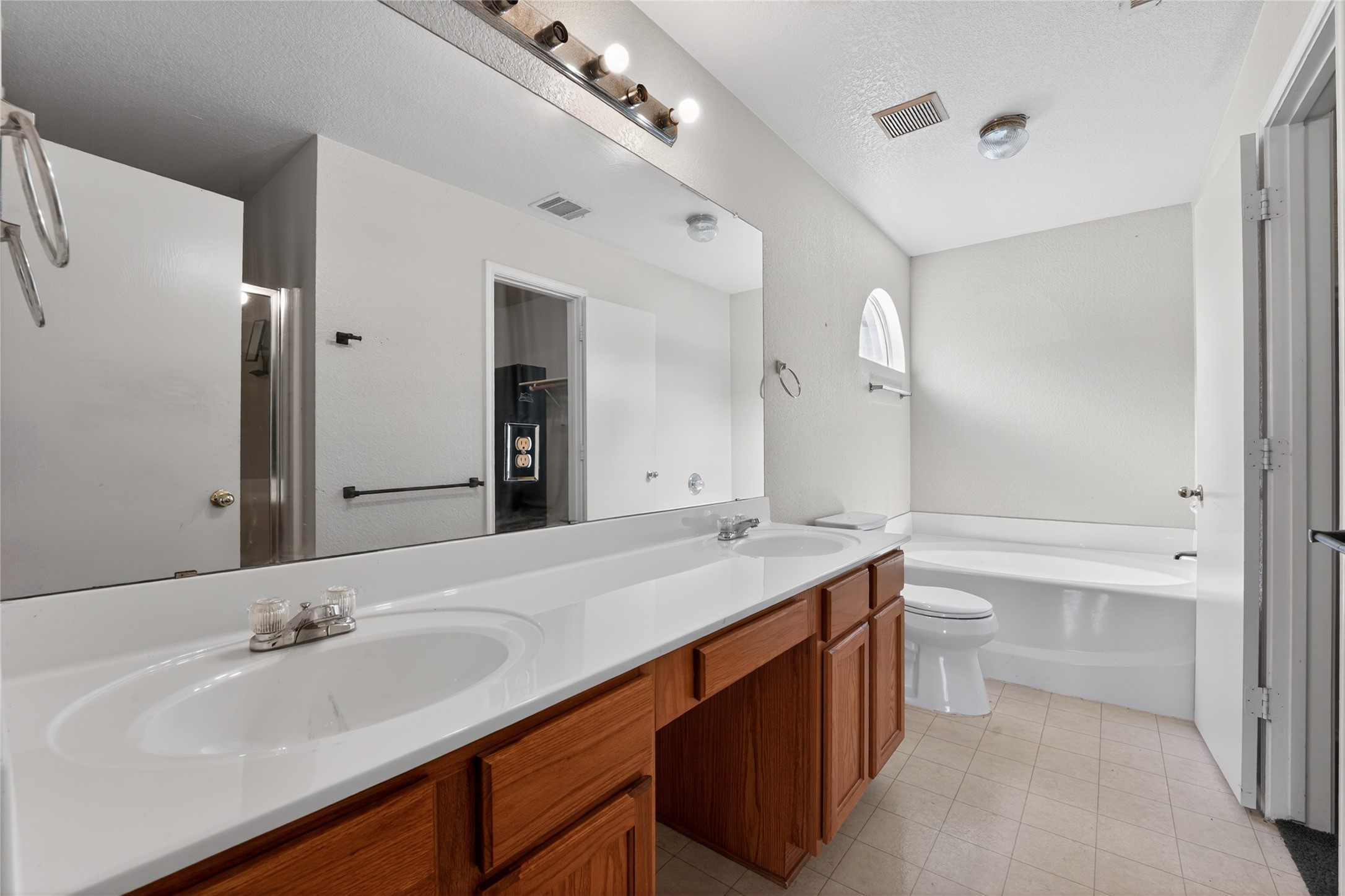 152 Eagle Drive Luling, TX 78648 - Photo 18 of 31 Bathroom featuring double vanity, a textured ceiling, a bath, and light tile patterned floors