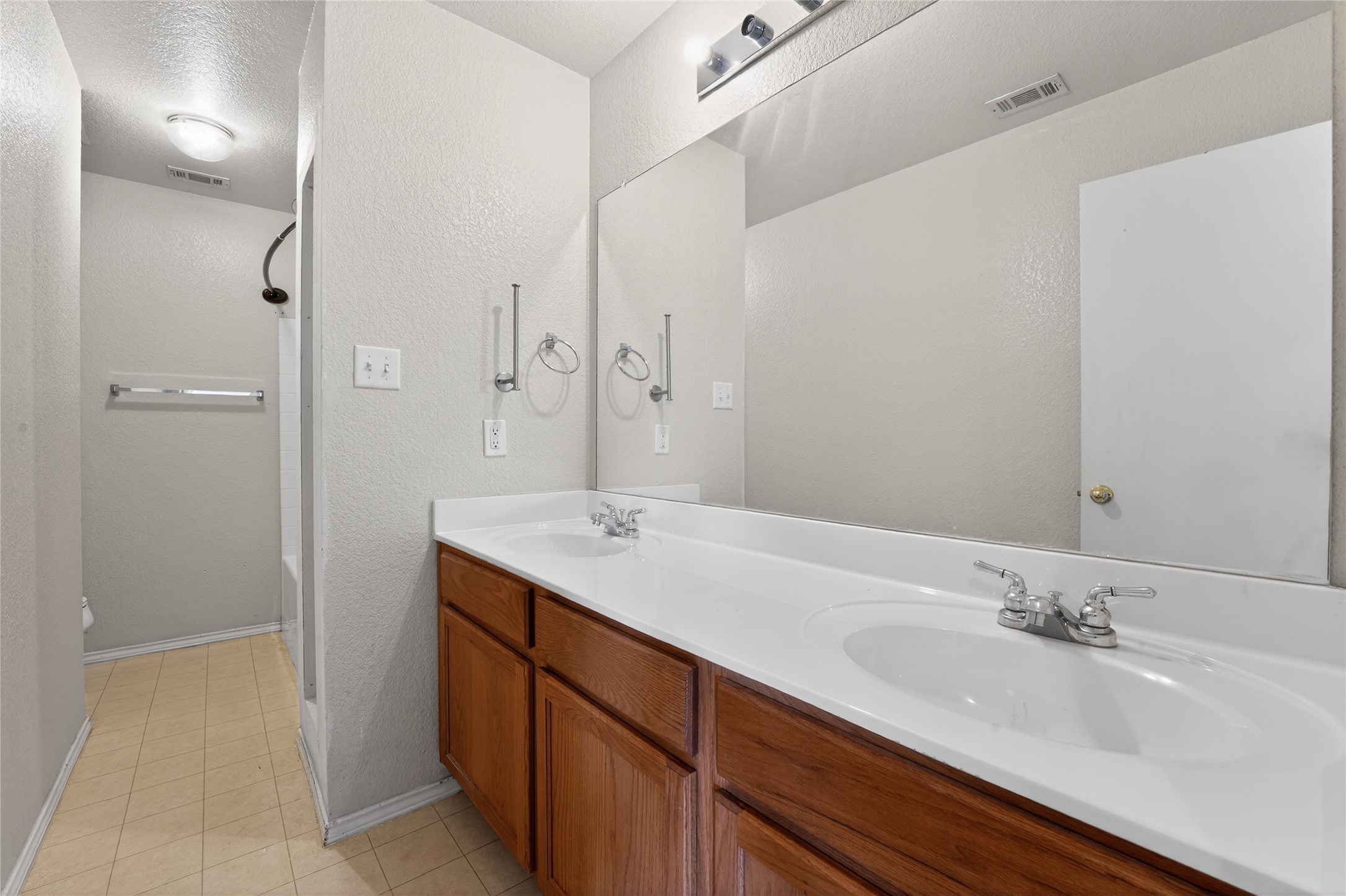 152 Eagle Drive Luling, TX 78648 - Photo 19 of 31 Bathroom featuring double vanity, a textured ceiling, a textured wall, and light tile patterned floors