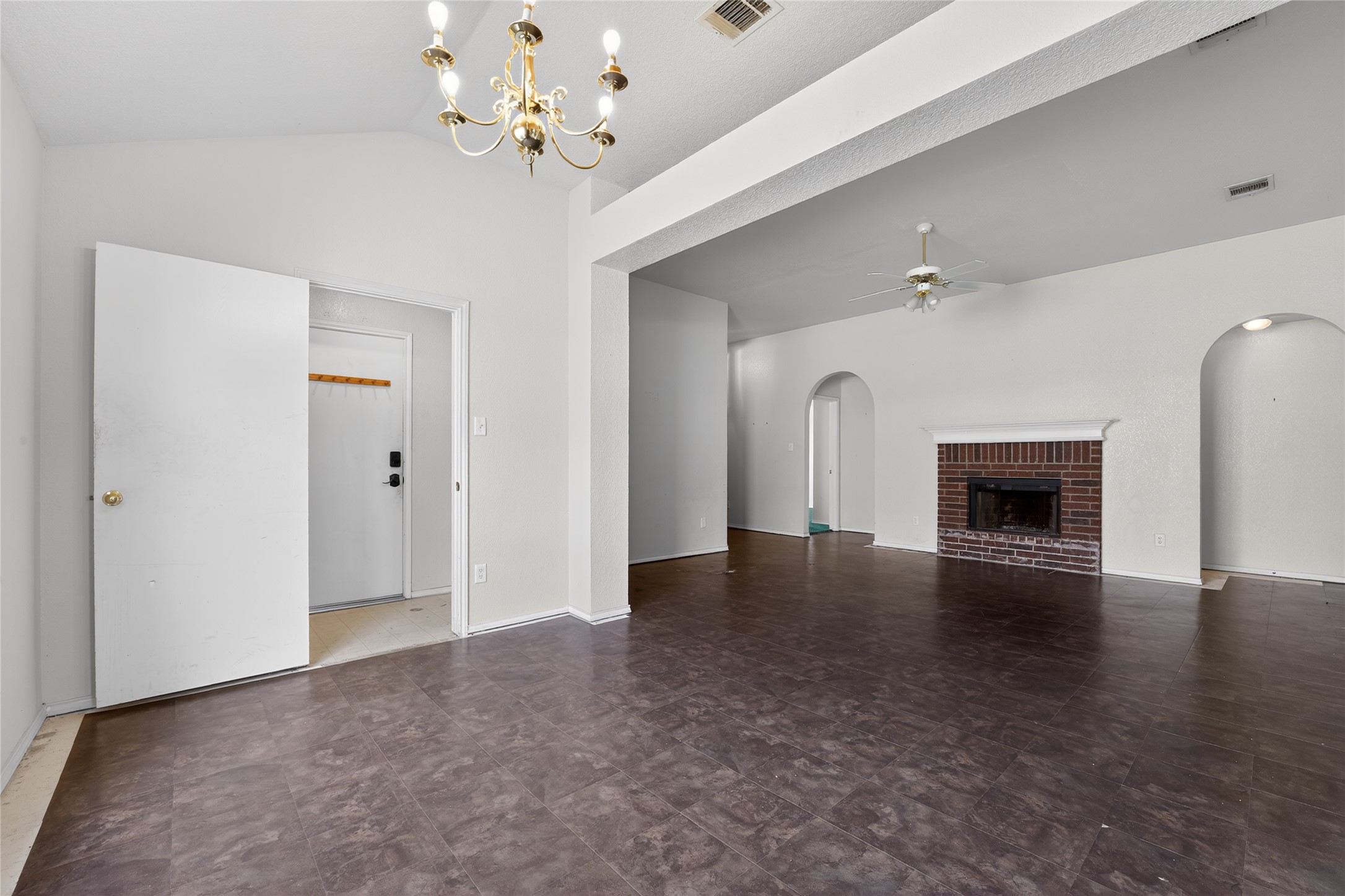 152 Eagle Drive Luling, TX 78648 - Photo 5 of 31 Unfurnished living room with a fireplace, a ceiling fan, lofted ceiling, and a chandelier
