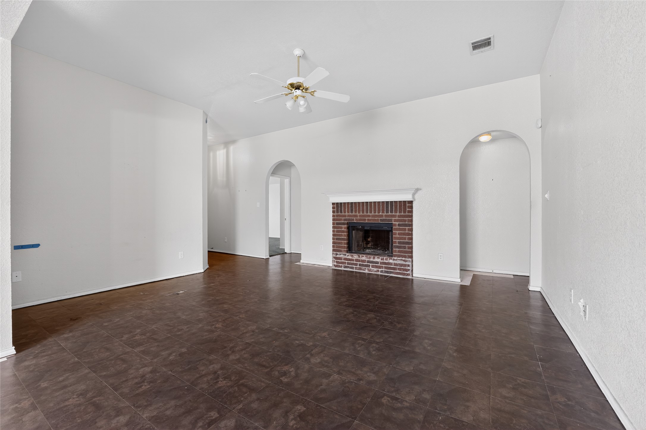 152 Eagle Drive Luling, TX 78648 - Photo 8 of 31 Unfurnished living room featuring a fireplace, ceiling fan, and arched walkways