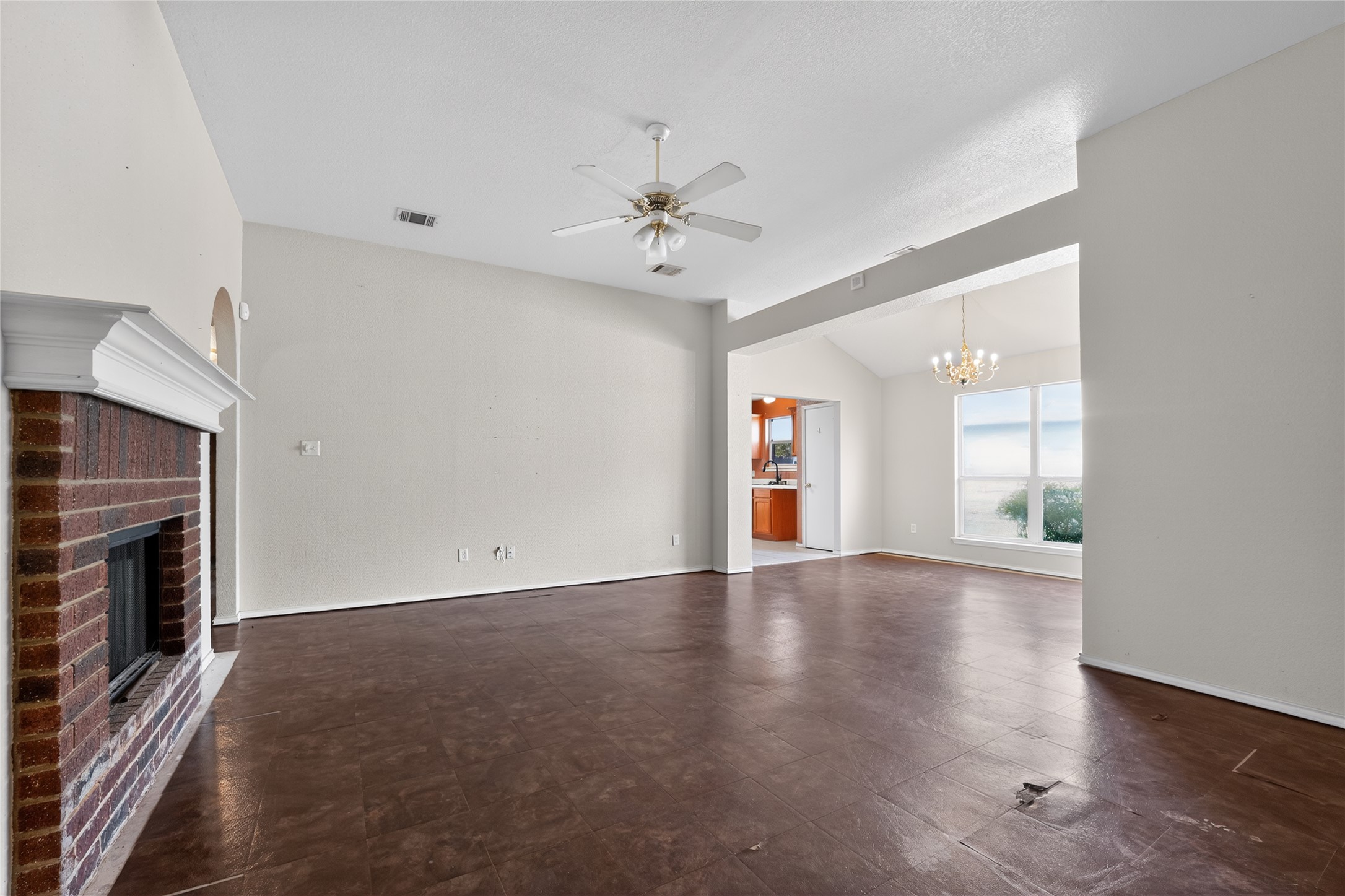 152 Eagle Drive Luling, TX 78648 - Photo 9 of 31 Unfurnished living room with a ceiling fan, suspended lighting, lofted ceiling, and a brick fireplace
