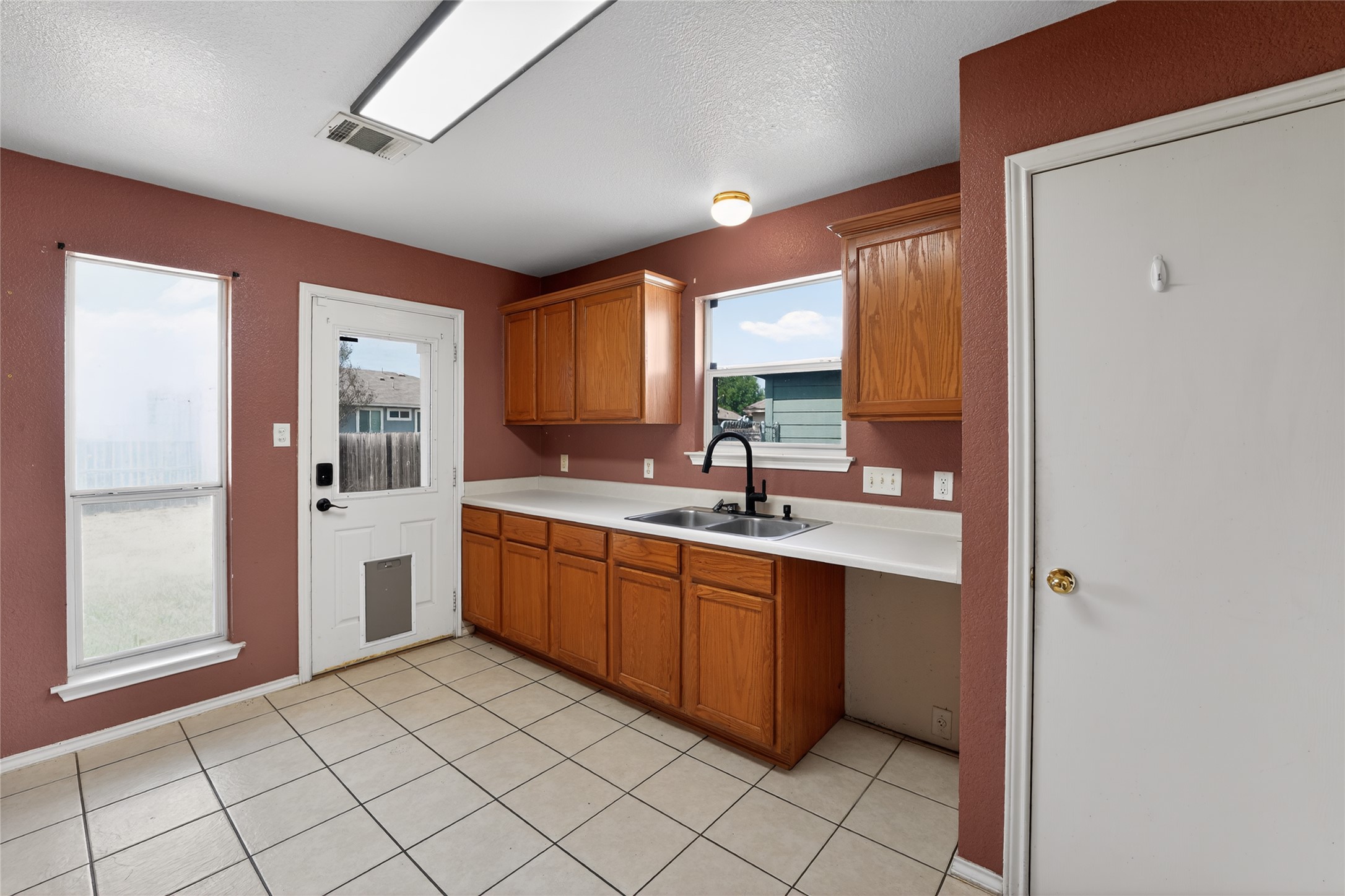 152 Eagle Drive Luling, TX 78648 - Photo 10 of 31 Kitchen featuring wood finish cabinets, light countertops, light tile patterned flooring, and a textured ceiling