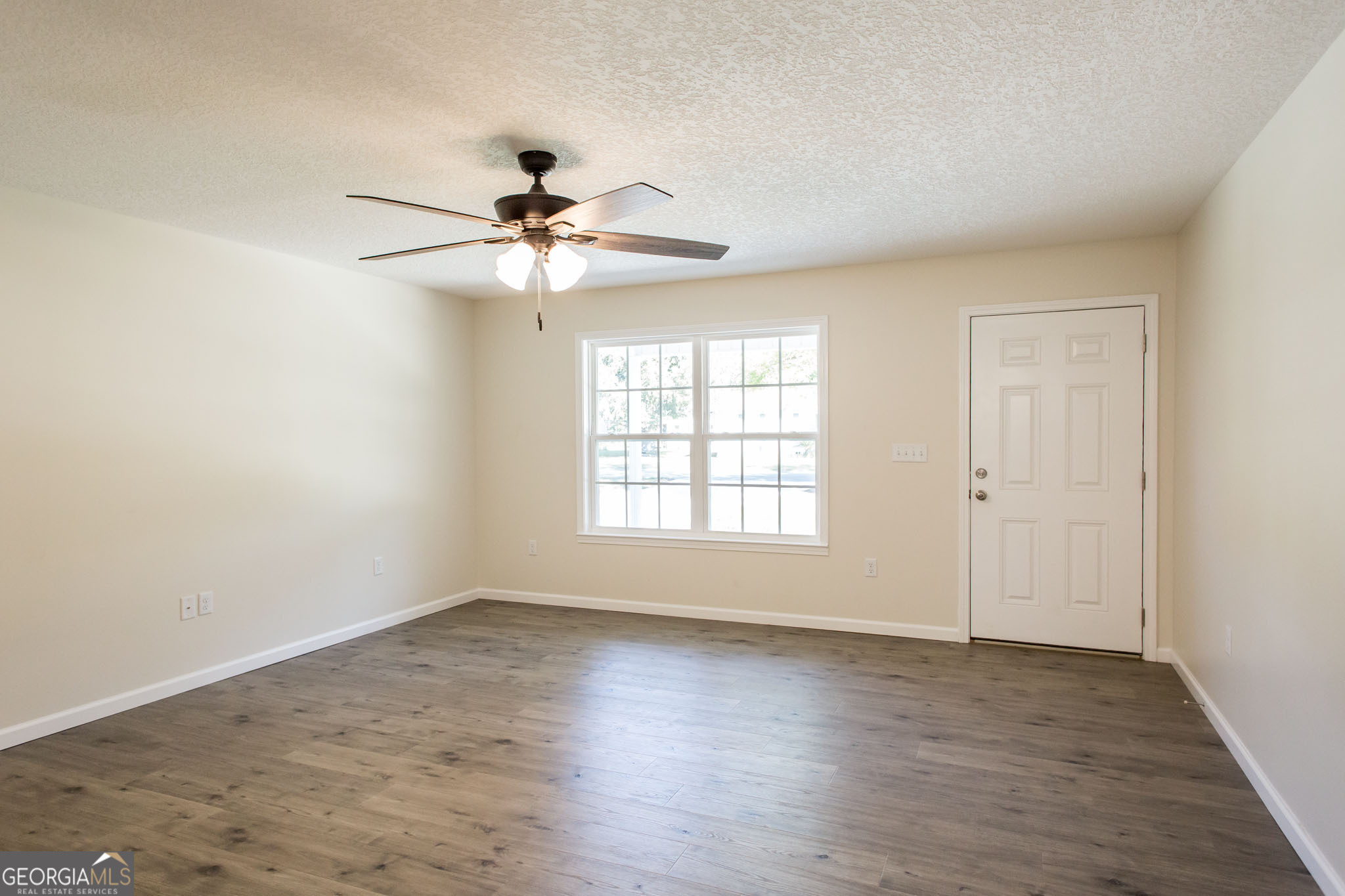 121 Union Street Waycross, GA 31501 - Photo 4 of 25 an empty room with wooden floor fan and windows