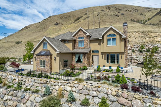 2543 East 700 South Springville, UT 84663 - Photo 56 of 73 Craftsman-style house featuring stone siding, stucco siding, a fenced front yard, a chimney, and a mountain view
