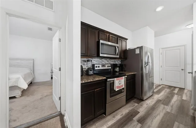 a kitchen with stainless steel appliances granite countertop sink stove refrigerator and cabinets