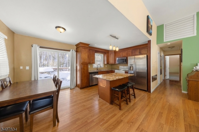 31 Meadow Lane Vernon, NJ 07462 - Photo 15 of 43 a kitchen with stainless steel appliances kitchen island granite countertop a table chairs in it and wooden floors