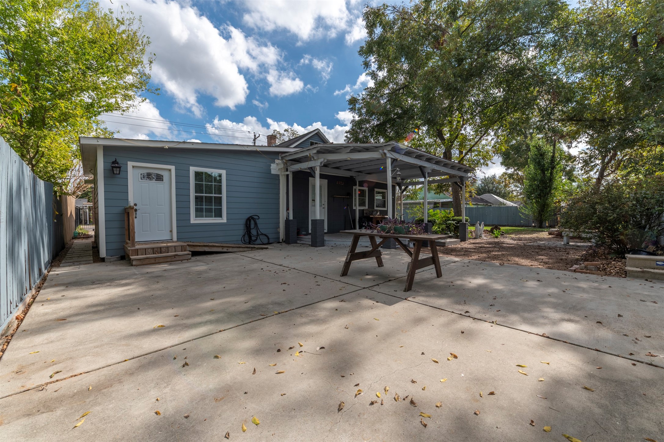 4303 Castor Street Houston, TX 77022 - Photo 28 of 41 a view of a backyard with a patio and a lawn chairs under a large tree