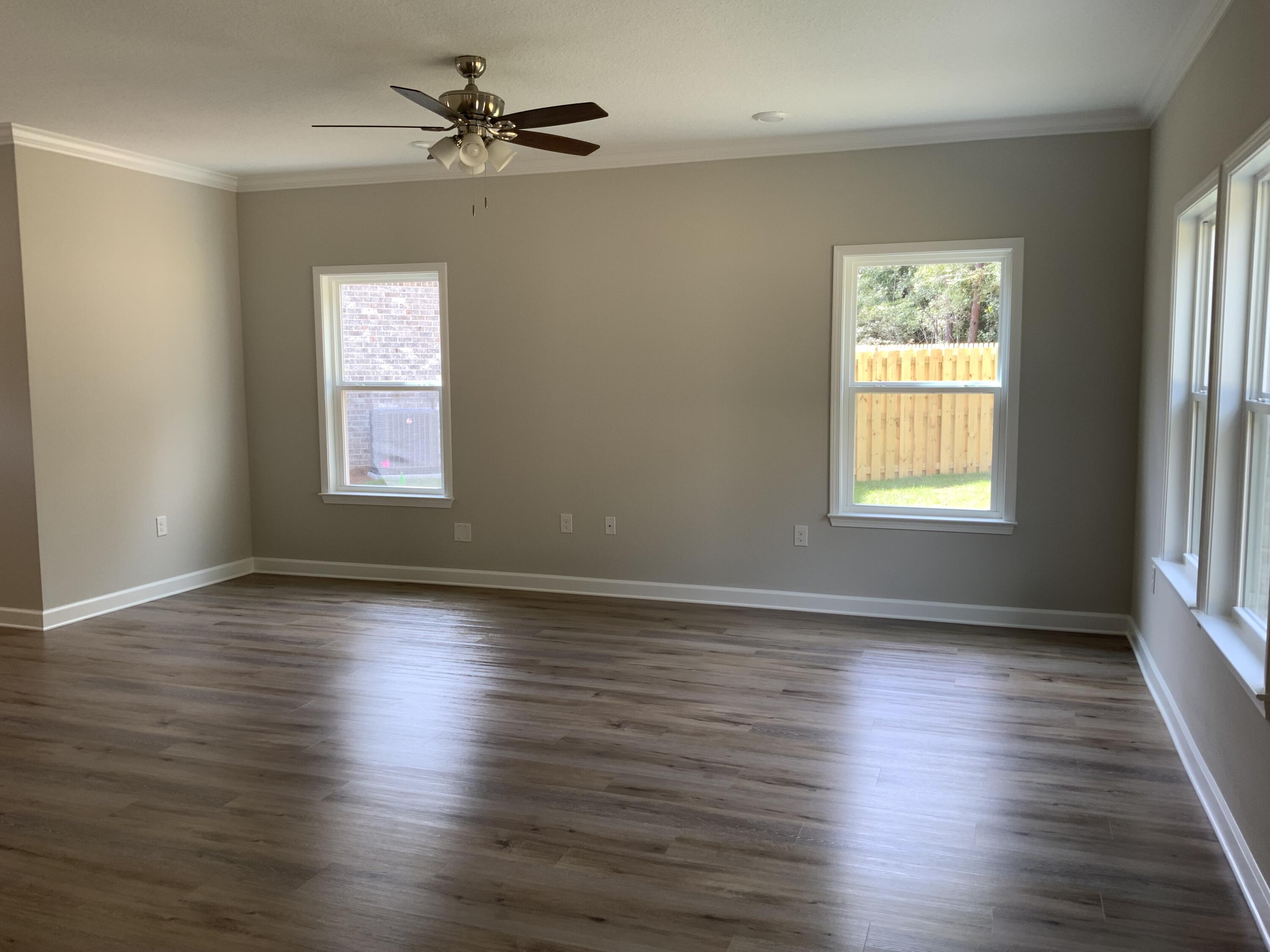 32 Laurel Oaks Drive Freeport, FL 32439 - Photo 3 of 11 an empty room with wooden floor chandelier fan and windows