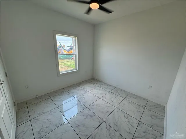 an empty room with windows and fan