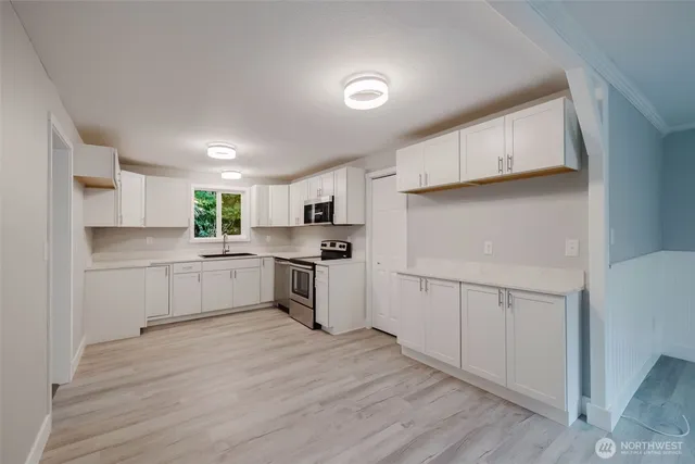 a view of a kitchen with white cabinets and wooden floor