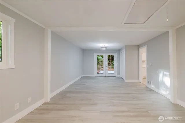 a view of an empty room with a window and a kitchen