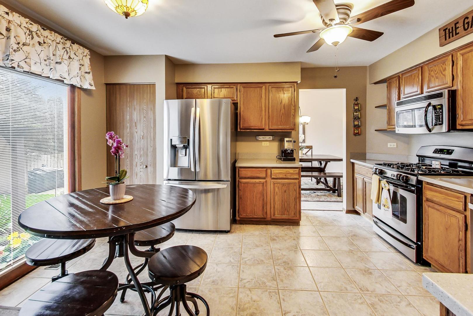 1174 Sweetwater Ridge Lake In The Hills, IL 60156 - Photo 10 of 44 a kitchen with stainless steel appliances kitchen island granite countertop a table chairs and a refrigerator