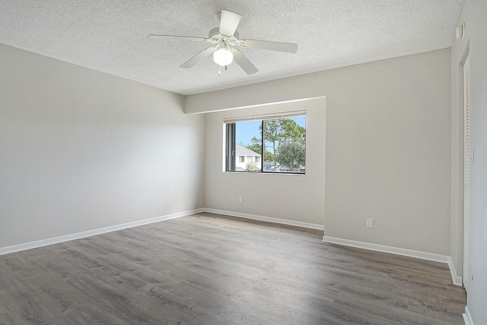 4206 Inlet Circle Greenacres, FL 33463 - Photo 11 of 30 an empty room with wooden floor ceiling fan and windows