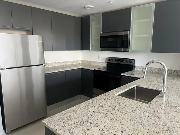 a kitchen with granite countertop a refrigerator and a sink