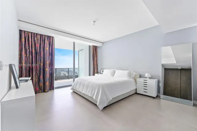 a spacious bedroom with a large bed and a chandelier